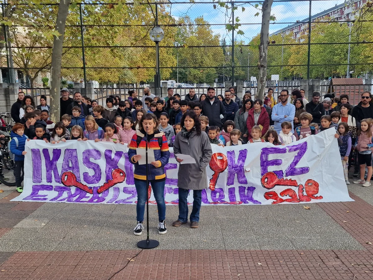 Concentración frente a Abendaño Ikastola con familias y pancartas reclamando vivienda, durante la lectura de un comunicado
