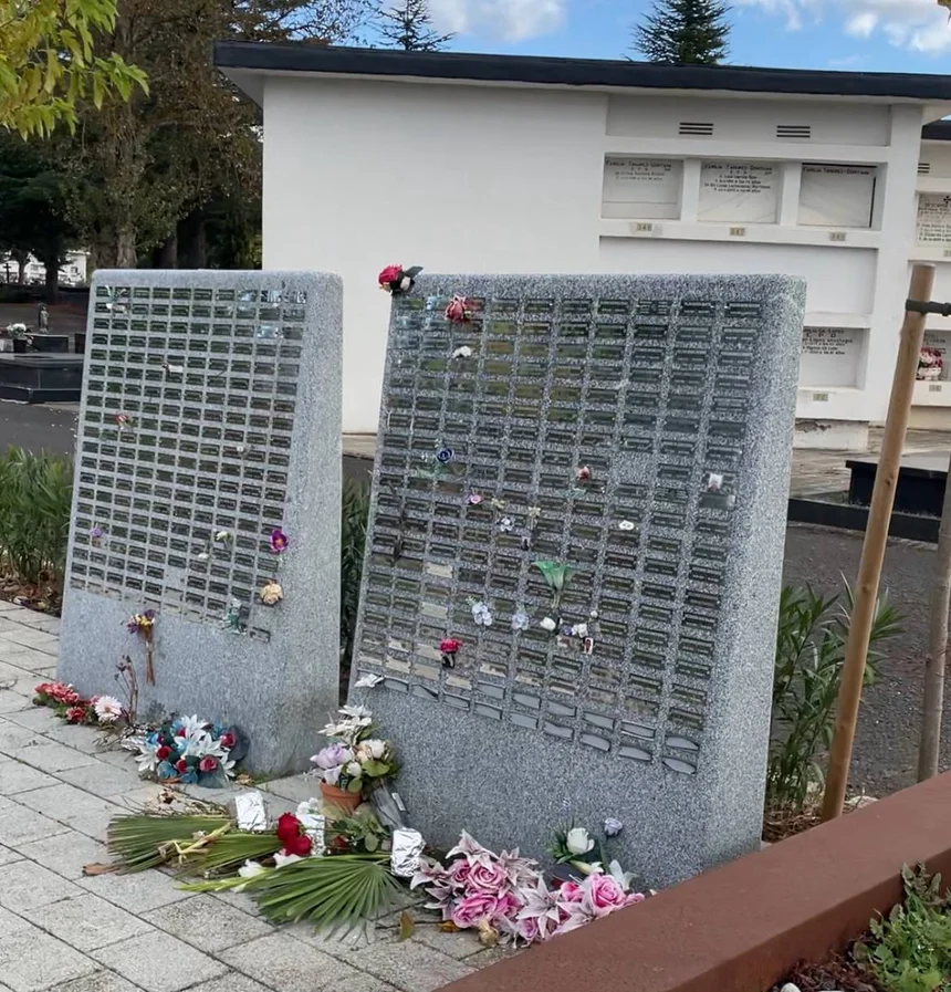 Dos estructuras de columbarios de piedra con placas y flores