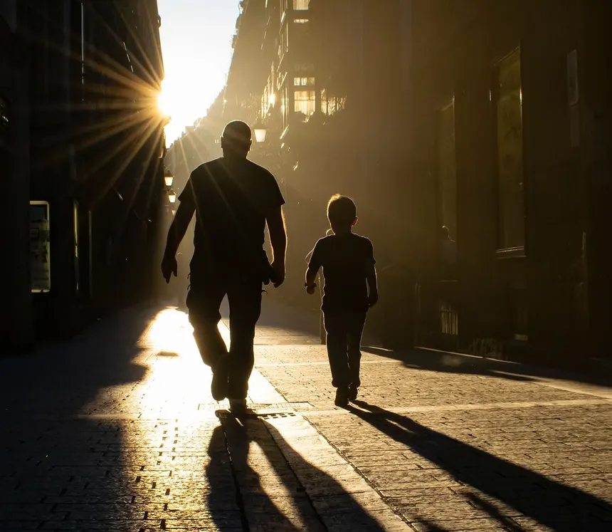 Adulto y niño caminando a contraluz por una calle de San Sebastián