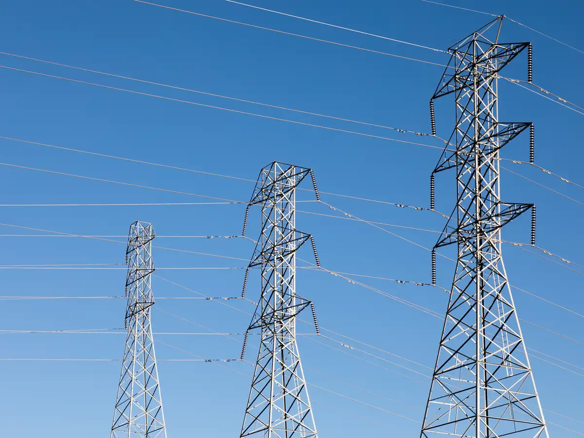 Torres de alta tensión Torres de alta tensión y líneas eléctricas bajo un cielo azul
