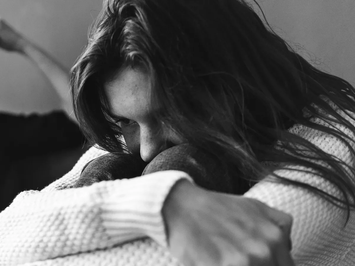 Violencia contra las mujeres en Álava, imagen de recurso Fotografía genérica en blanco y negro de una mujer sentada, con la cabeza apoyada sobre las rodillas